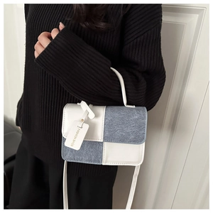 Detail of color-block square crossbody bag featuring a fashion tag and textured stitching