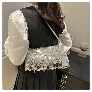 Close-up of silver sequined shoulder bag with elegant slim strap worn by a model