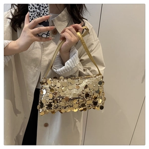 Close-up of golden sequins on a luxury underarm bag with metallic texture and leather strap