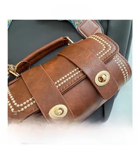 Detail of vintage brown leather bag showing gold twist locks and ethnic pattern strap