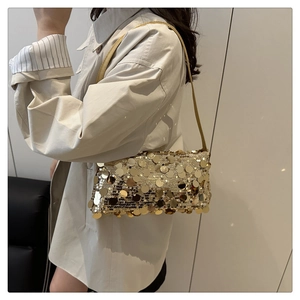 Close-up of sparkling golden sequins on a minimalist shoulder bag with fine straps