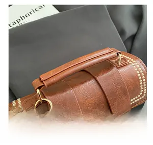 Detail of brown leather Boston bag showing lychee grain texture and gold metal hardware