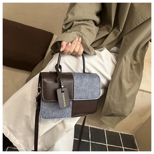 Detail of color-block square bag showing leather stitching and textured wool fabric