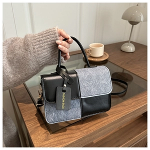Detail of color-block square handbag with grey felt and black leather stitching