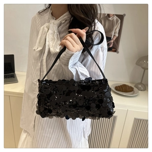 Detail of a chic black sequin shoulder bag featuring large circular shimmering sequins