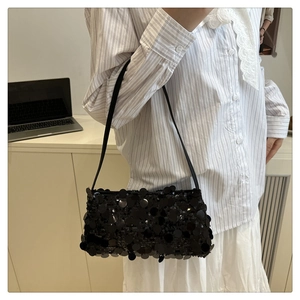 Detail shot of a black sequin baguette bag with adjustable strap and glossy texture