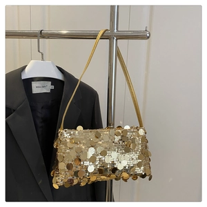 Detail of shimmering gold sequin baguette bag with metallic texture and shoulder strap