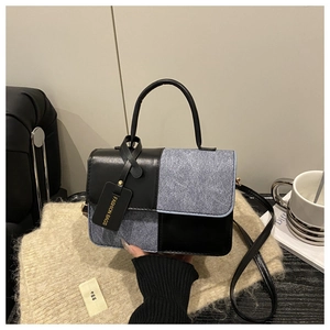 Detail of color-block crossbody bag featuring blue tweed, black leather, and fashion tag