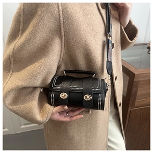 Detailed look of a black Boston barrel bag with rivet studs and embroidered strap