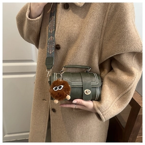 Detail of dark green cylinder bag with silver studs and a colorful jacquard wide strap