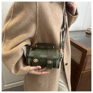 Close-up of dark green vintage cylinder bag with beaded edges and jacquard ethnic strap