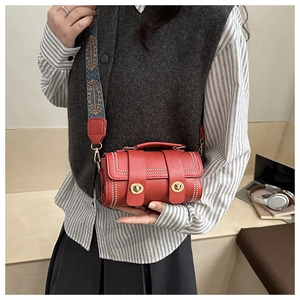 Close-up of red leather Boston bag featuring white contrast stitching and a gold swivel lock