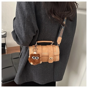 Close-up of retro cylinder crossbody bag with ethnic jacquard strap and plush charm
