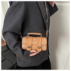 Detail of brown leather cylinder bag featuring vintage rivets and boho patterned strap