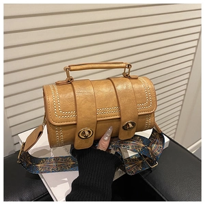 Detail of vintage barrel bag with golden studs and a colorful patterned wide strap