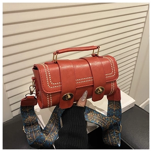 Detail of red Boston bag with gold rivets and vintage geometric pattern strap