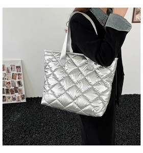 Gros plan d'un sac cabas argenté métallisé matelassé avec texture brillante et anses en tissu