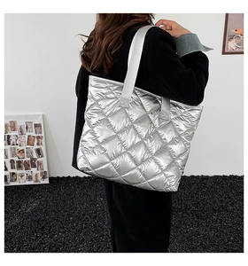 Sac cabas argenté matelassé avec fini métallisé, porté à l'épaule dans un style moderne