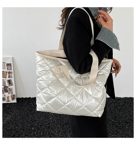 Sac fourre-tout matelassé argenté avec doubles anses porté par un mannequin chic