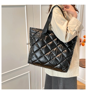 Détail du sac fourre-tout matelassé noir sur modèle montrant la capacité et le nylon doux