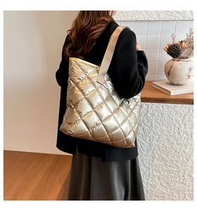 Sac fourre-tout matelassé or champagne porté par un mannequin dans un décor intérieur