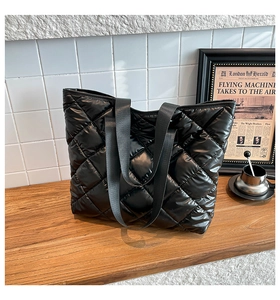 Gros plan détaillé d'un sac cabas en nylon matelassé noir avec motif à losanges sur bois