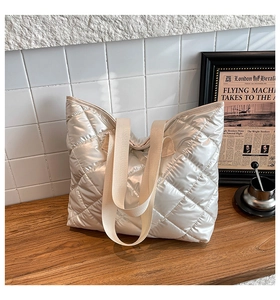 Gros plan sur la texture matelassée argentée du sac cabas et sa large sangle