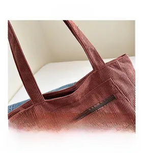 Detail shot of corduroy tote bag featuring a front zipper pocket and reinforced handles
