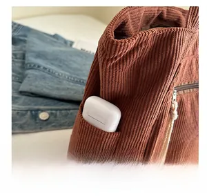 Detail view of corduroy tote side pocket showing storage space with wireless earbuds