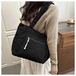 Detail of black corduroy tote bag showing front zipper pocket and retro texture