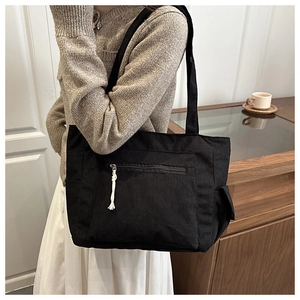 Detail of black corduroy tote bag showing fine ribbed texture and front zipper pocket