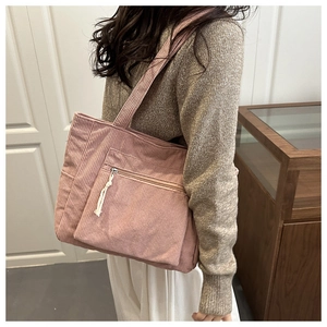 Detail of pink corduroy tote bag featuring vertical ribs and a front zipper pocket