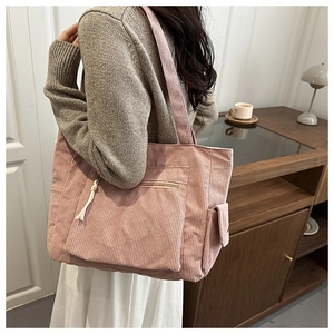 Detailed view of pink corduroy tote bag showing front zipper pocket and side buckle pocket