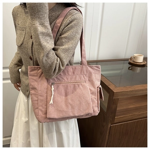 Close-up of pink corduroy tote bag with functional zipper pocket and side pocket design