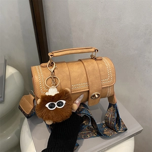 Retro khaki cylindrical Boston bag with colorful ethnic strap and plush monster charm