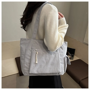 Detailed side view of grey corduroy tote bag with zipper pocket and braided puller