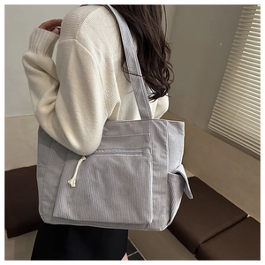 Detail of light gray corduroy tote bag with side pocket and cotton rope zipper puller