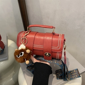 Brick red faux leather crossbody bag with geometric wide strap and plush pendant charm