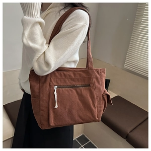 Detailed texture of caramel corduroy tote bag showing large front pocket and zipper detail
