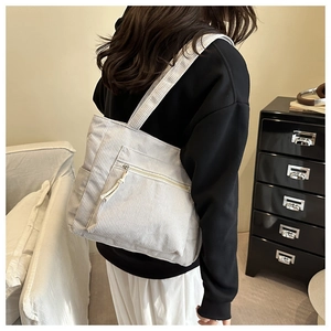 Detail of white corduroy tote bag with front zipper pocket shown in a lifestyle setting