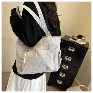 Detail of a large off-white corduroy tote bag with side pockets in a retro lifestyle setting