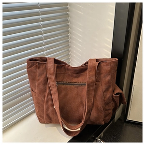 Close-up of brown corduroy tote bag featuring vertical ribs and a front zipper pocket