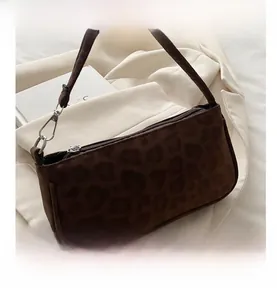 Detail view of leopard print baguette bag with silver buckles on white blazer