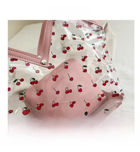 Detail of transparent PVC tote bag with cherry print and pink leather handle with studs
