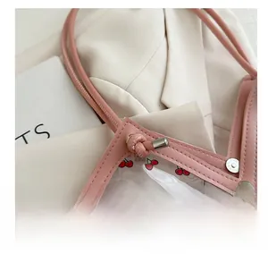 Detail of pink PVC tote bag featuring cherry prints and silver metallic rivets
