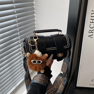 Close-up of black leather handbag with gold studs and colorful geometric strap