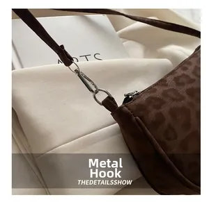 Detailed view of silver metal hook and leopard print suede fabric on shoulder bag