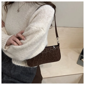 Close-up of leopard print baguette bag in brown suede fabric shown on shoulder