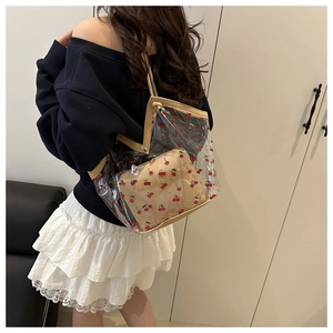 Detailed view of transparent cherry print tote bag with a beige inner pouch and leather trim