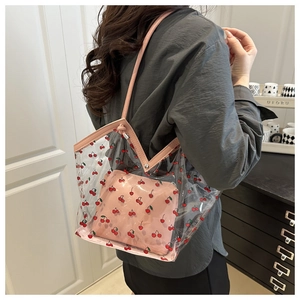 Detailed view of clear PVC tote with cherry print and inner pink pouch on person
